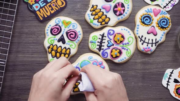 Step by step. Flat lay. Decorating sugar skull cookies with different color royal icing.