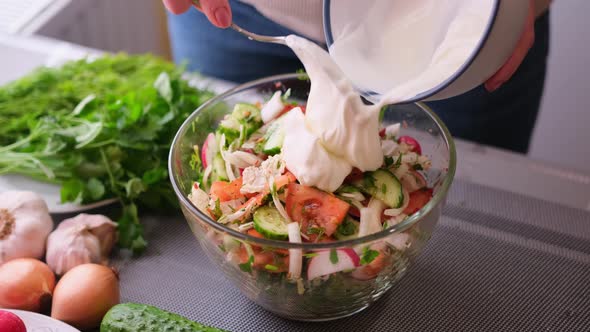 Woman Adding Sour Cream to Mixed Salad of Vegetables  Tomatoes Cucumbers Onion Parsley