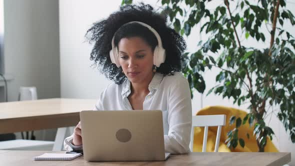 Portrait of African American Woman Talking on Video Conference Call Using Laptop and Headphones