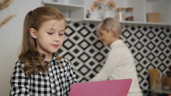 Small Girl Using Modern Digital Tablet While Mother Making Homew