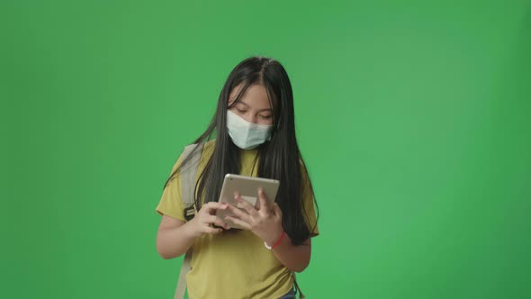 Asian Girl Student Wearing A Mask And Use Tablet While Walking To School On Green Screen Chroma Key