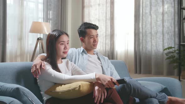 Young Asian Couple Relaxing And Watching Tv At Home