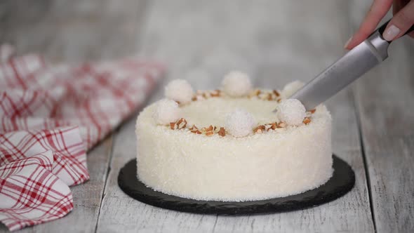 Cutting a Delicious Coconut Mousse Cake Decorated with Candy and Almond