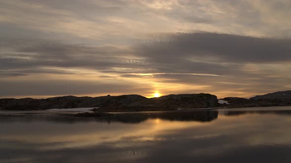 Sunset timelapse with reflections in mountain lake and silhouette of tent