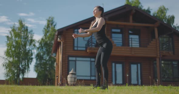 Young Athletic Girl Performs Squats in the Fresh Air