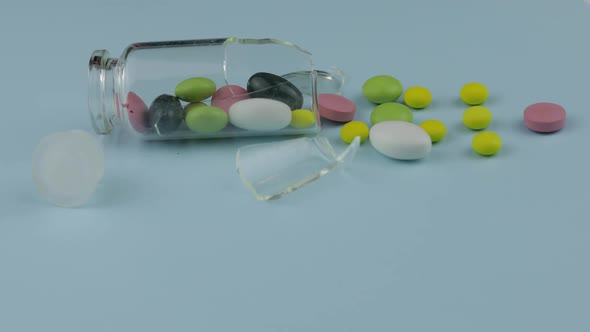 Broken Glass Jar with Many Different Pills and Drugs Spinning on Blue Background