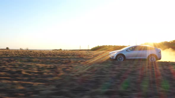 Aerial Shot of Electrical Car Move on Off-road Route Leaving Dust Trail Behind. Modern Auto Driving