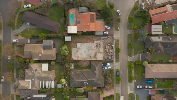 Drone perspective of white car arriving at suburban home.