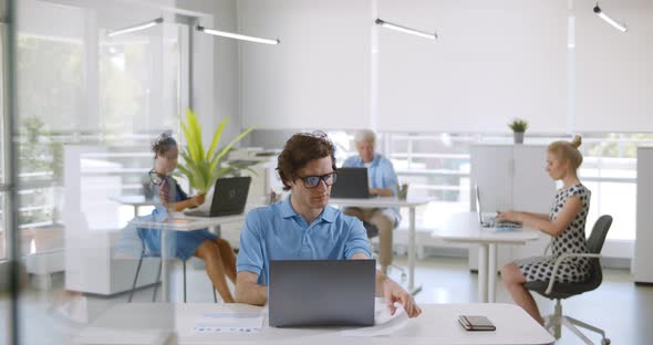 Multiethnic People in Smart Casual Sitting at Desk and Working on Computer in Modern Office