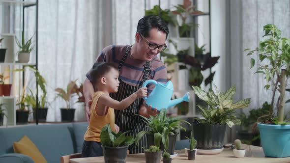 Asian Man With Son Holding Watering Pot To Water The Plants At Home