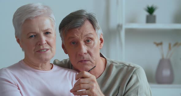 Elderly Lively Emotional Couple Sitting on Couch Records Video Message Grey Haired Man Points with