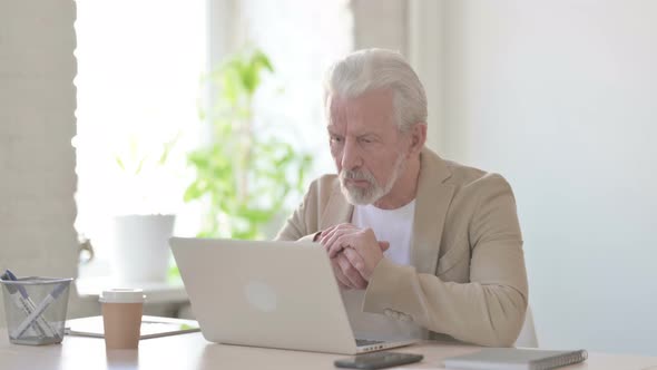 Old Man Thinking While Working on Laptop in Office