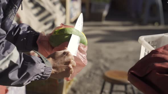 Man Using Knife To Slice Skin From Mango