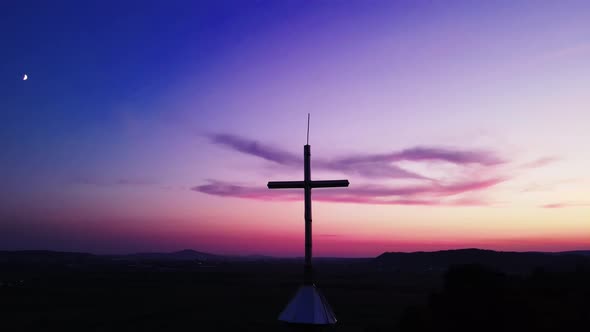 Silhouette of orthodox church cross against pink sunset sky