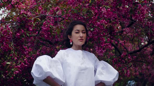 Fashion Portrait of a Young Beautiful Woman in a White Dress Standing and Posing Next to a Red