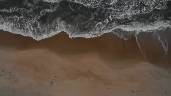 Aerial view of a beach with strong waves coming in