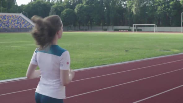 Athletic Young Girl Runs in the Stadium. Slow Motion