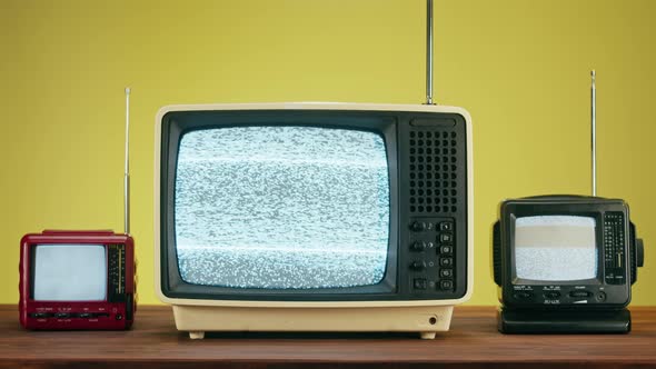 Old Televisions with Grey Interference Screen on Yellow Background