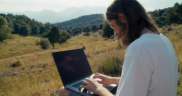 Man Using Portable Modern Device on Summer Mountain Journey