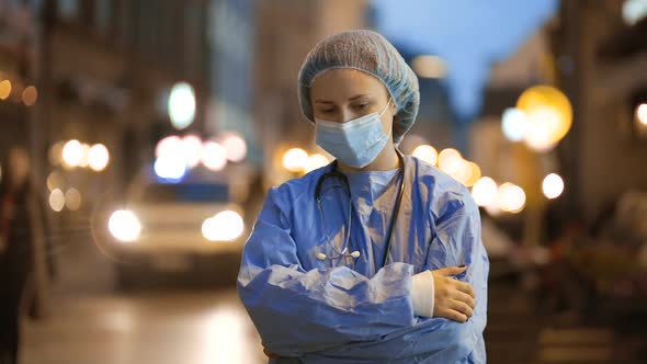 Sad Medical Doctor or Student Stands During Emergency Accident with Ambulance Passing By