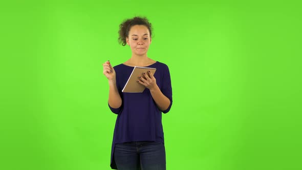 Curly Woman Thinking, Then Writing with Pencil in Notebook. Green Screen