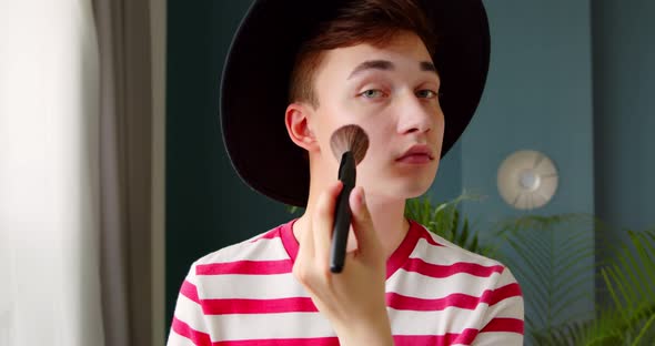 Young transgenger queer man make up beauty routine standing in front of camera