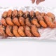 Close up a human hand picks up grilled river prawns from a pile on foil. - VideoHive Item for Sale