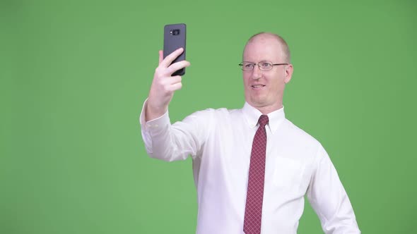 Happy Mature Bald Businessman Taking Selfie