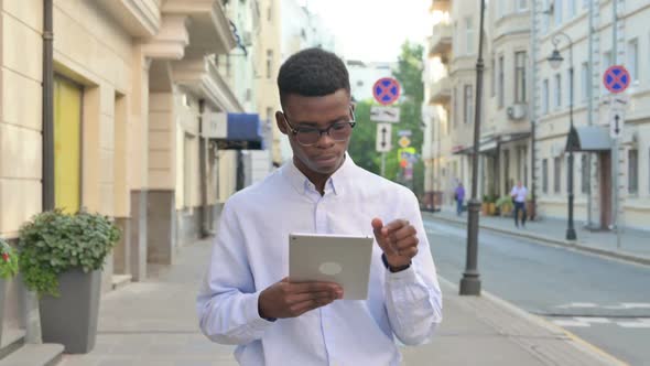 African Man Working on Tablet While Walking on the Street