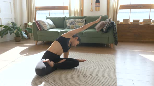 Young Indian Woman Meditating Sitting on Carpet and Doing Stretching exercise doing Yoga