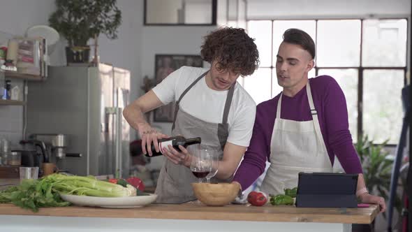 Happy Gay Couple Having Fun at Home Drinking and Cooking Together in the Kitchen