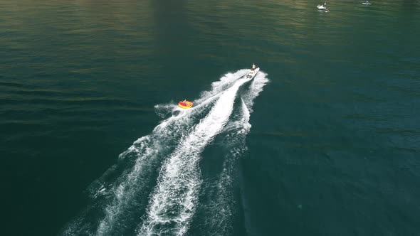 Happy People are Going to Swim on an Air Mattress Behind a Jet Ski