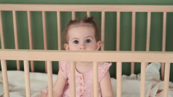 Funny Toddler Sits in a Crib and Smiles