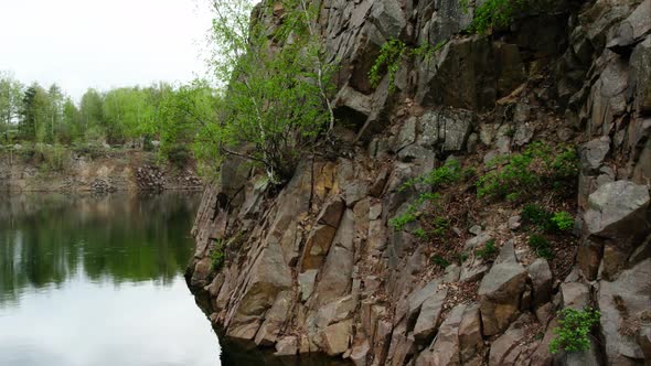 Drone rise over quarry pond in drizzle