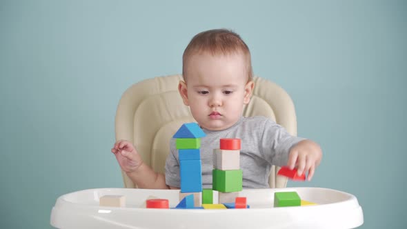 Toddler 12-17 months old playing with a wooden cube constructor sitting on a chair