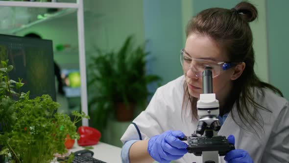 Biologist Scientist Looking at Green Leaf Sample Under Microscope