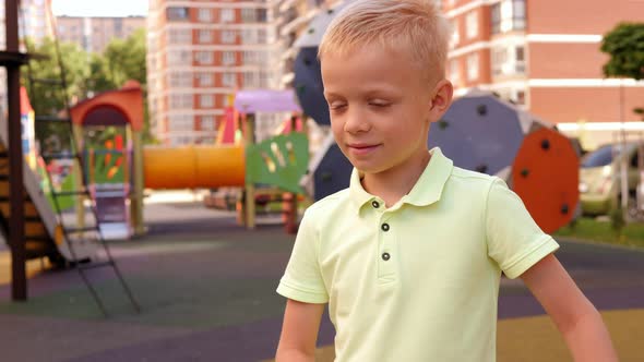 Closeup of a Boy with Blond Hair Having Fun and Dancing on a Modern Playground