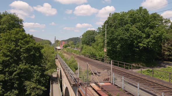 Freight train heading off into the distance viewed from a rusty old train trestle. Wide angle slow z