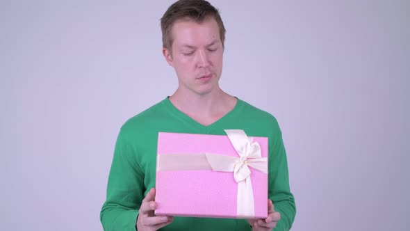 Happy Young Handsome Man Thinking with Gift Box Ready for Valentine's Day