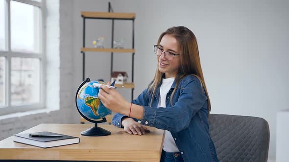 Happy Handsome Woman Moving toy Plane in the Air to the Globe