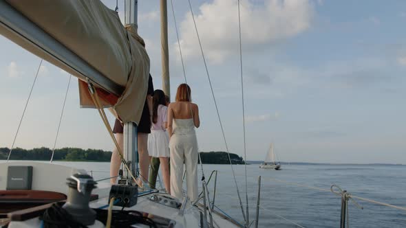 Friends are Standing on the Bow of a Sailing Boat and Drinking Wine