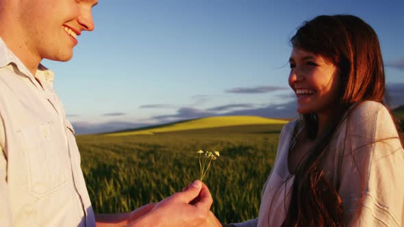 Man offering flower to woman in field