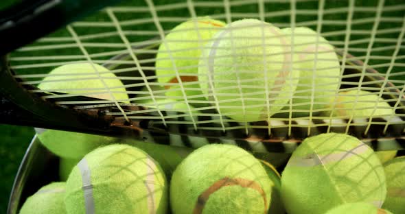 Tennis balls and racket in bucket at studio 4k