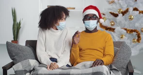 Webcam View of Mixed Race Family in Medical Protective Masks Sitting in Living Room Near Christmas