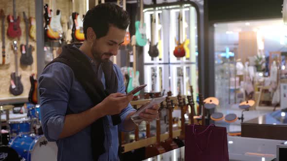 A Middle Eastern Man Using Mobile Phone To Purchase Product 