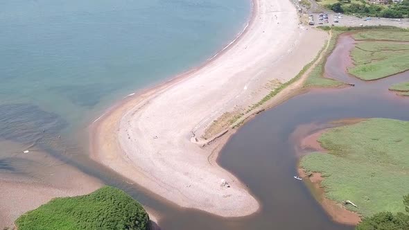 STATIC CROP Aerial, flying over River Otter, beach, and ocean toward coastal town in England