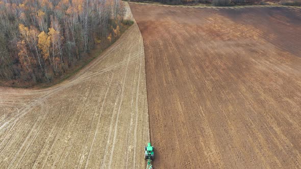 Agricultural Work In Field Tractor Plough Soil Ground With Plow After Harvesting