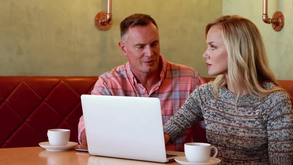 Couple using laptop while having coffee 4k