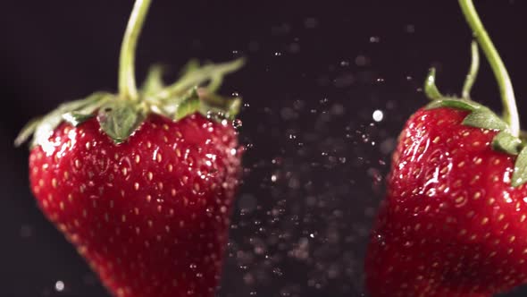 Two Big Strawberries are Flying and Colliding on a Black Background