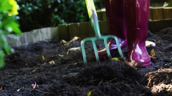 Senior woman digging with garden fork